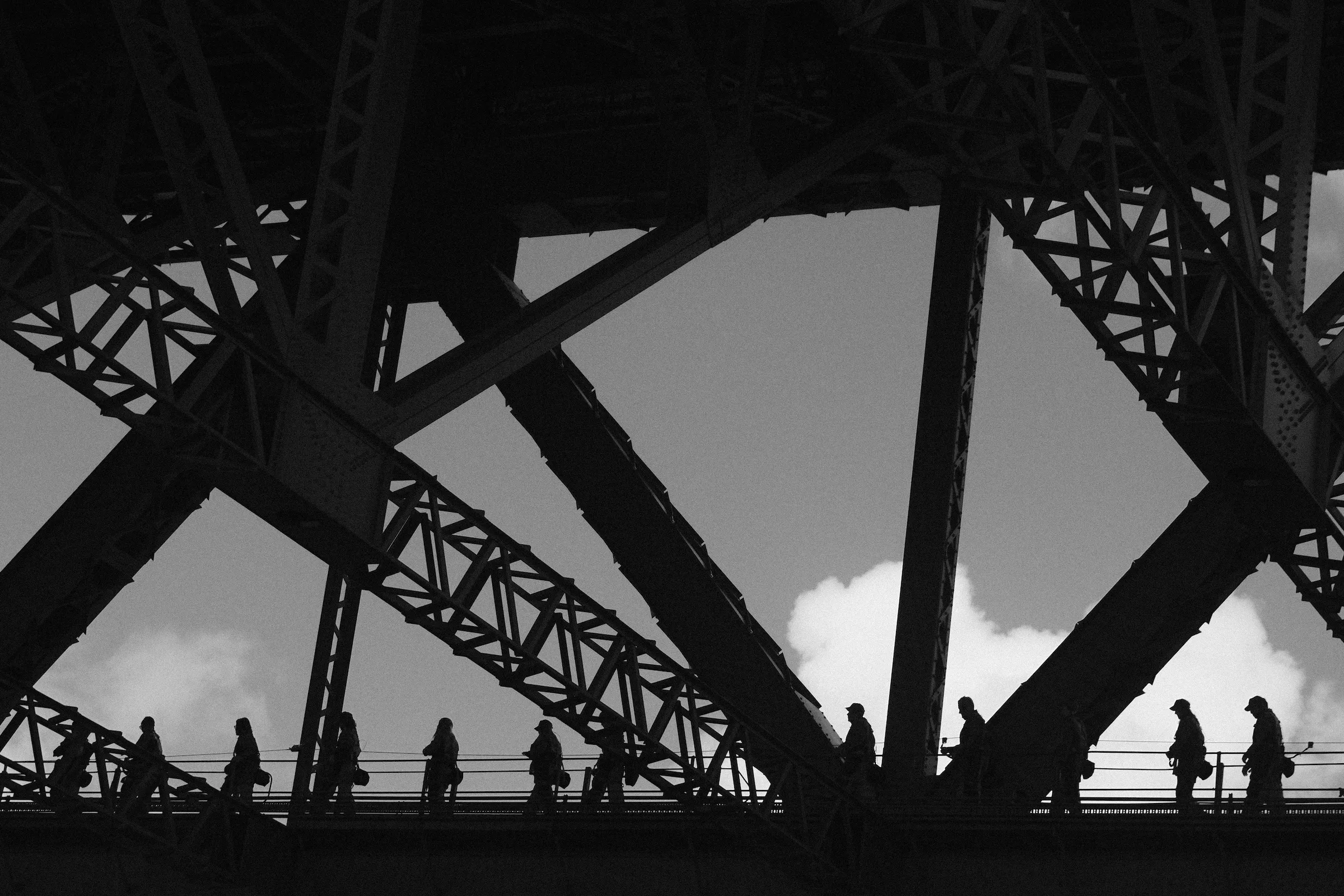 silhouette of people walking on bridge